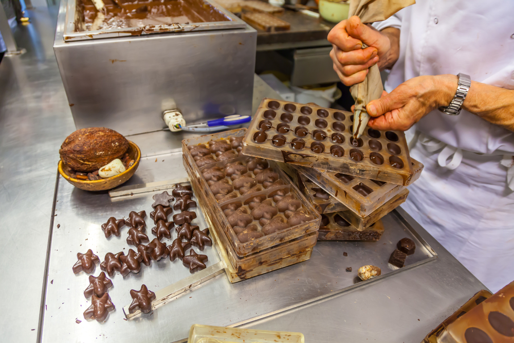 Chocolate confectioner doing a chocolate presentation with cocoa beans, cocoa pods and chocolate molds at chocolate museum in Brussels, Belgium