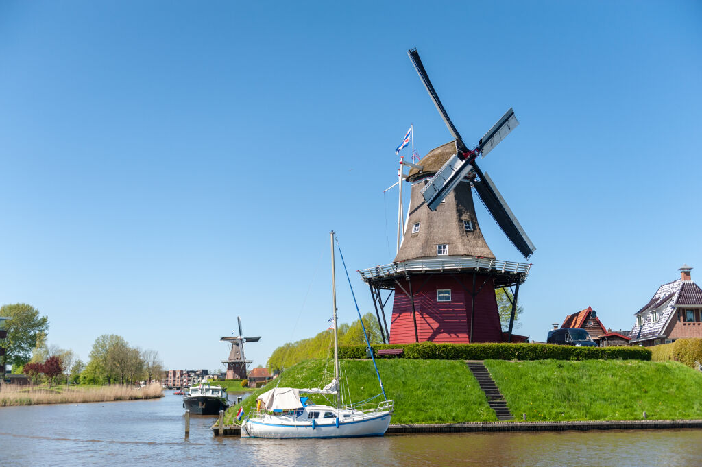 Klasyczny holenderski wiatrak w mieście Dokkum we Fryzji, w północnej części Holandii, widziany w jasne, słoneczne wiosenne popołudnie.