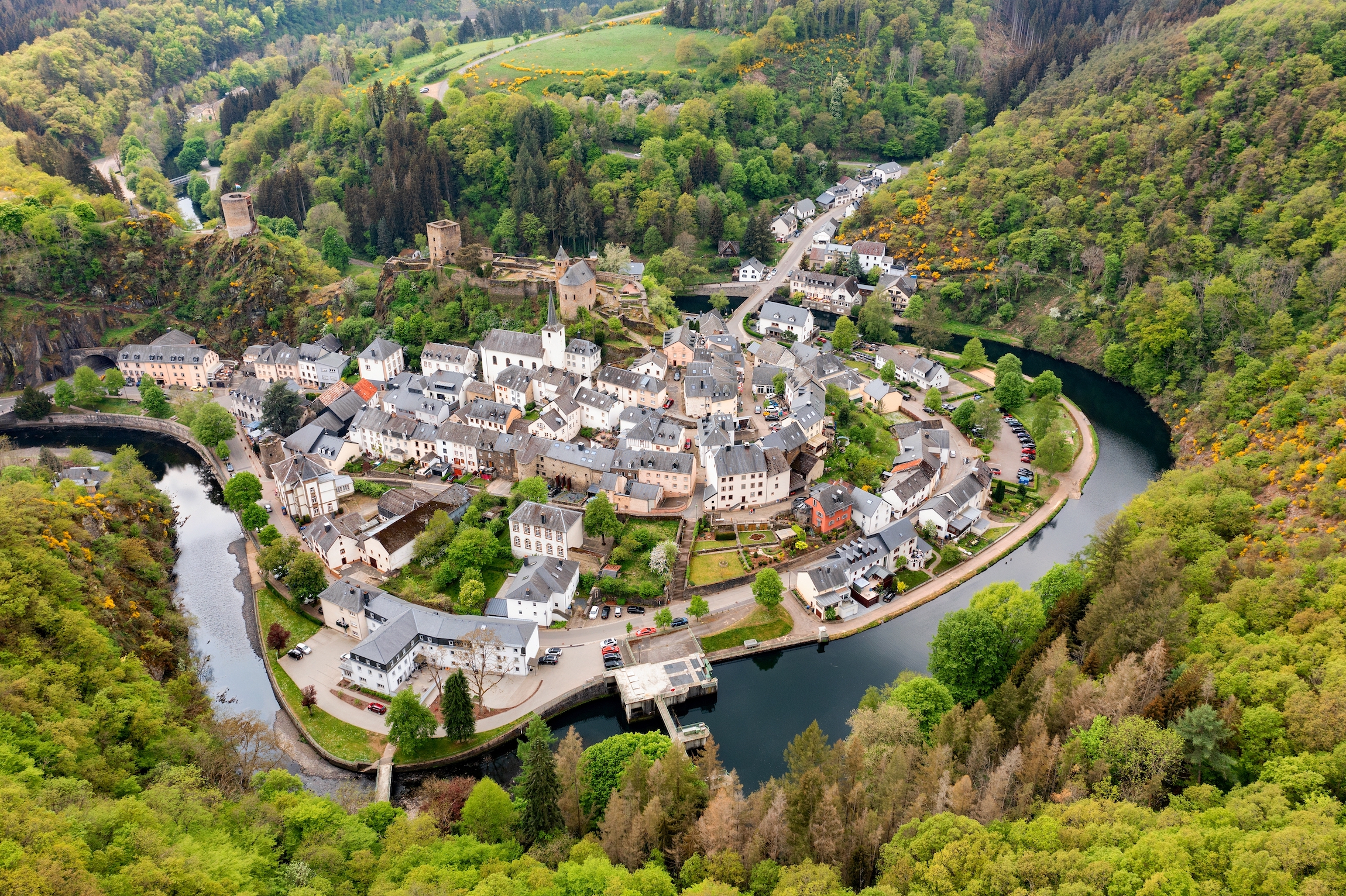 Widok z lotu ptaka na Esch-sur-Sure, średniowieczne miasto w Luksemburgu, zdominowane przez zamek, kanton Wiltz w Diekirch. Lasy Parku Przyrody Upper-Sure, meander krętej rzeki Sauer, w pobliżu jeziora Upper Sauer.