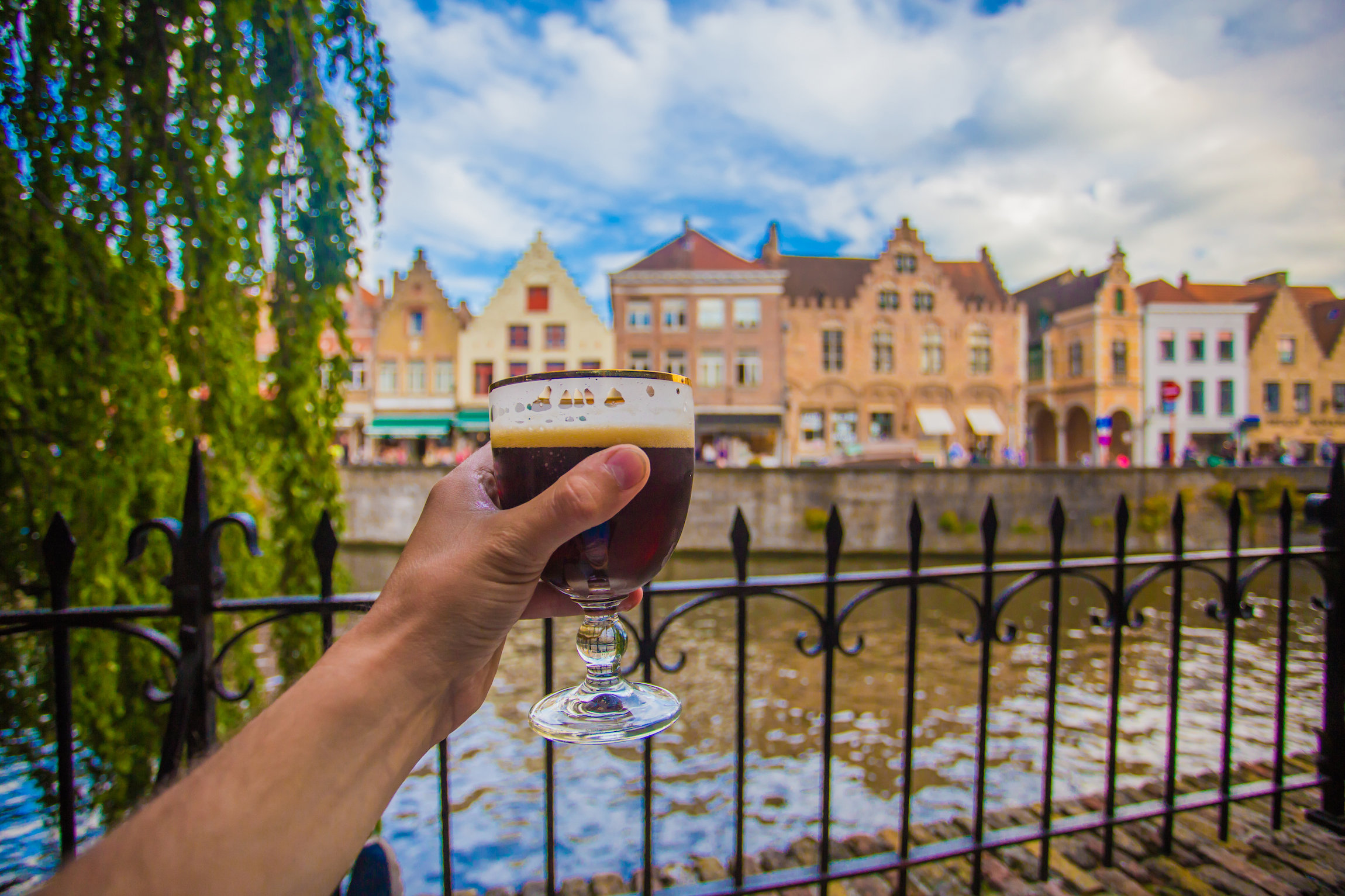 Pełna szklanka piwa na tle Brugii. Ręcznie z kieliszkiem do piwa w Brugii, Belgia.