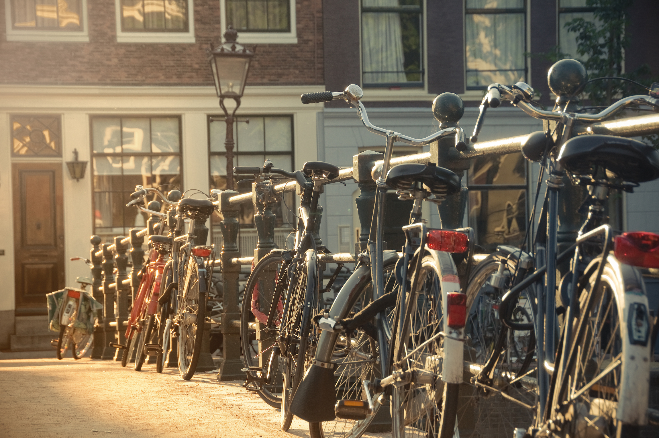 Rząd rowerów przy poręczy mostu w Amsterdamie, Holandia, o zachodzie słońca, Dlaczego warto jechać do Amsterdamu