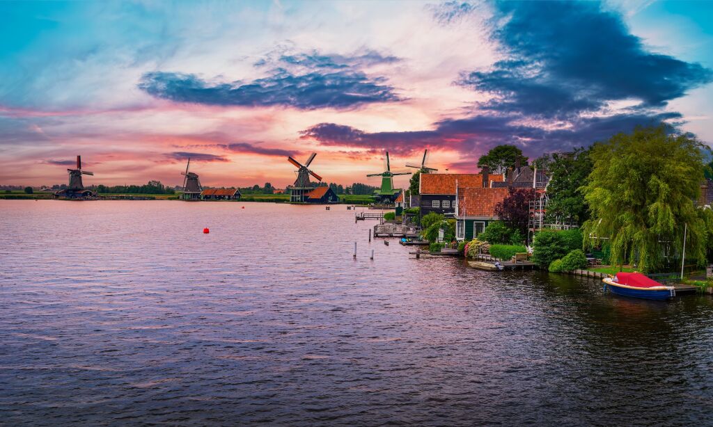 Zachód słońca nad zabytkowymi domami i wiatrakami w holenderskiej wiosce Zaanse Schans niedaleko Amsterdamu w Holandii.