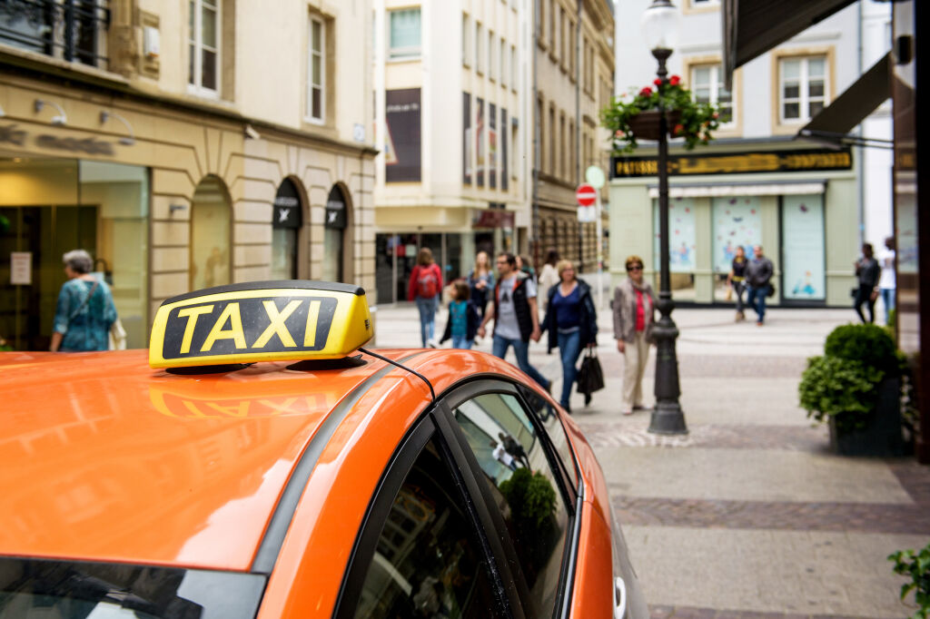 Taksówka czekająca na pasażera w centrum Luksemburga z ludźmi i turystami podziwiającymi miasto