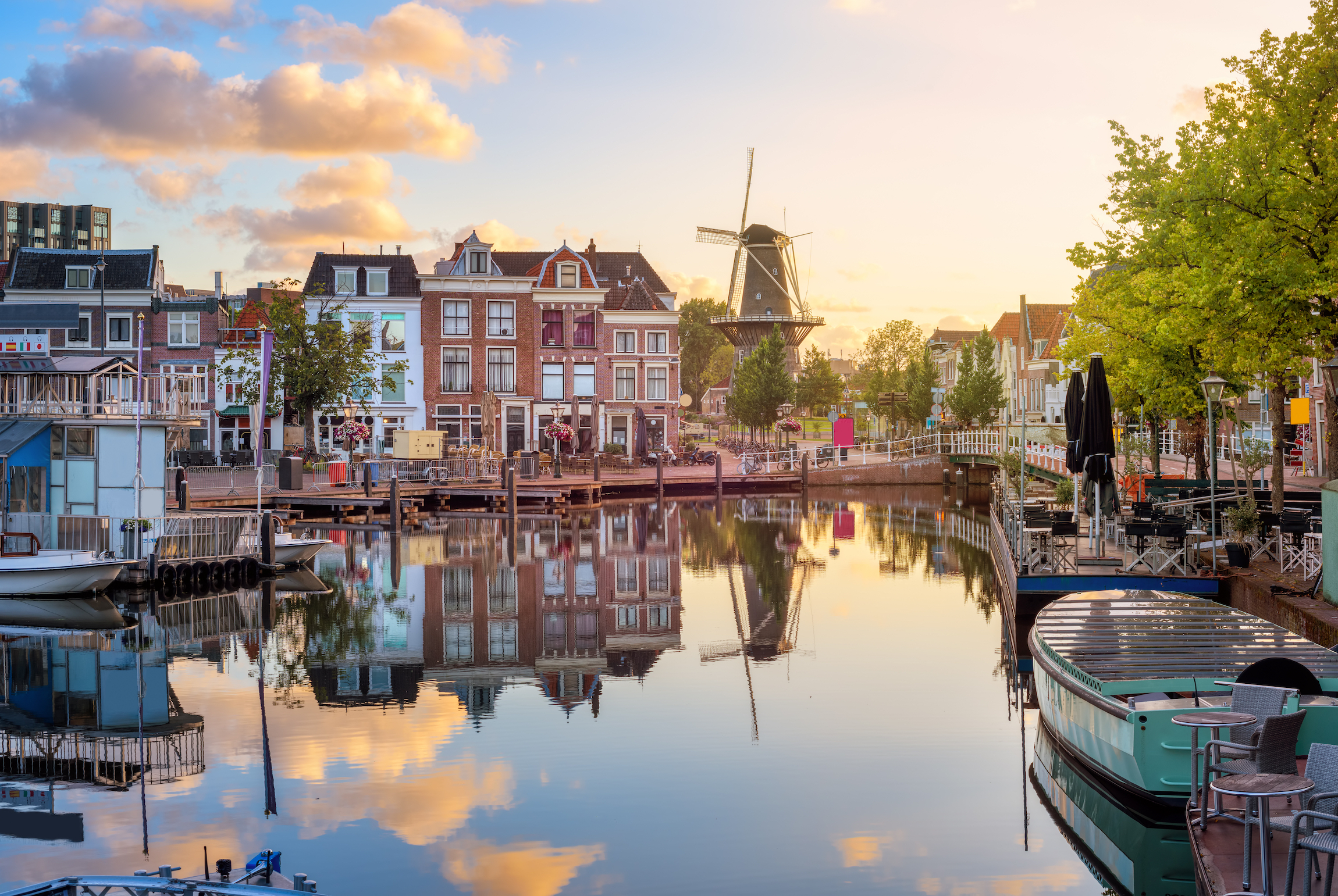 Stare miasto w Lejdzie, widok na Beestenmarkt i młyn De Valk odbijający się w rzece Ren o wschodzie słońca, Holandia Południowa, Holandia