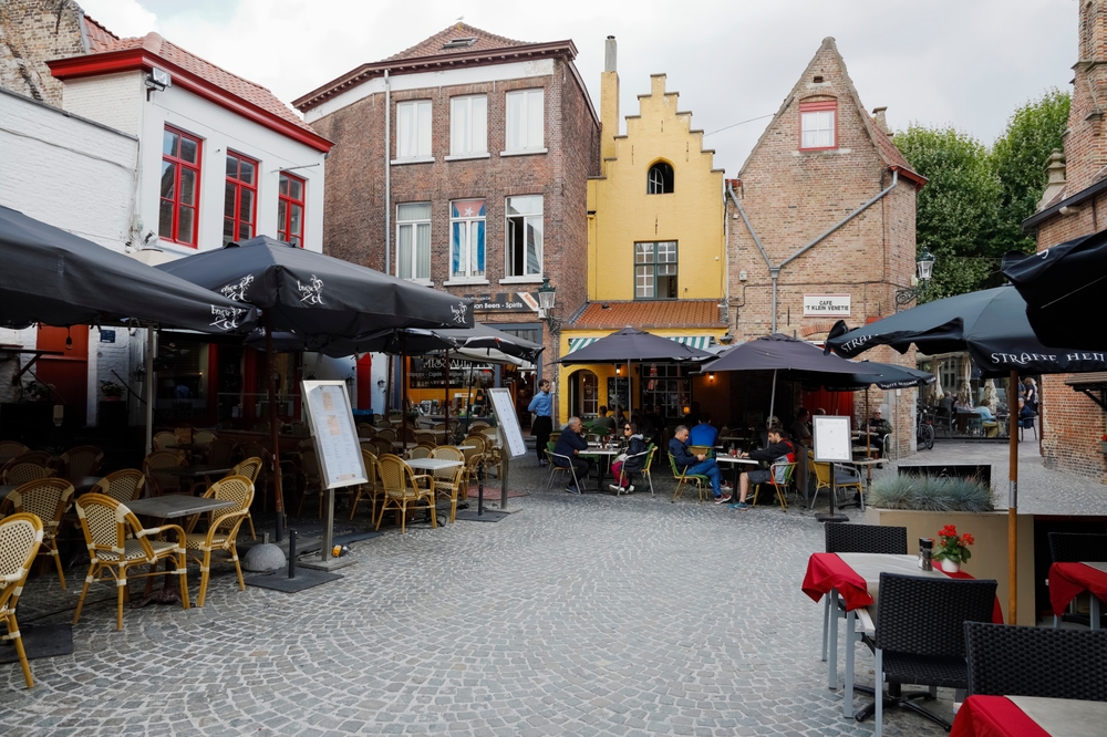 Bruges, Belgium - September 8, 2022: Outdoor restaurants and cafes are located inside, around a small town square surrounded by brick houses